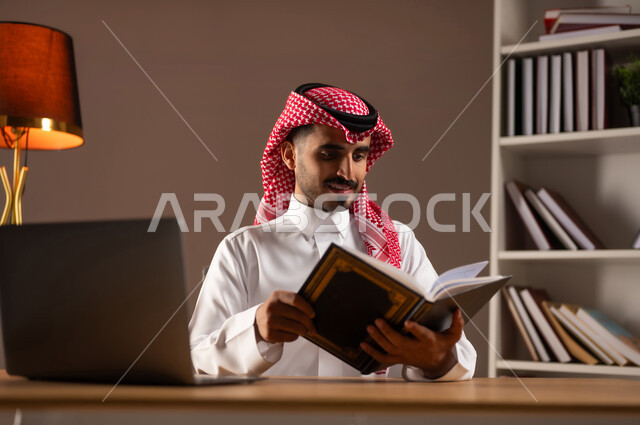 الاستمتاع بالأنشطة المفيدة في وقت الفراغ, مفهوم الثقافة والتعلم الذاتي, ممارسة هواية المطالعة, قراءة القصص والروايات, بورتريه مقرب لرجل عربي خليجي سعودي يرتدي الثوب التقليدي والشماغ يحمل بيده كتاب, استخدام الأجهزة والتطبيقات الالكترونية الحديثة, خلفية بيج
