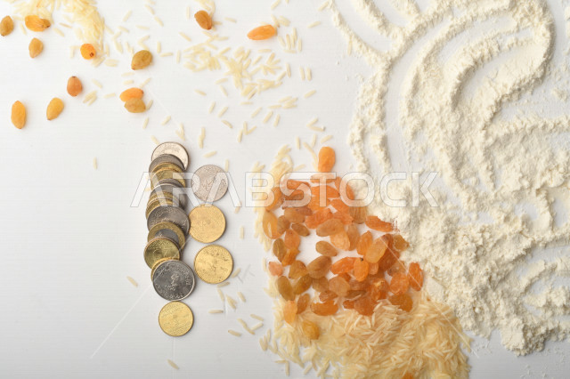 مجموعة من الأرز والزبيب والقمح والطحين والعملات المعدنية على خلفية بيضاء