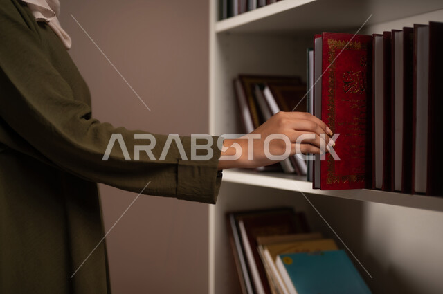 ممارسة الهوايات المفيدة, مفهوم القراءة والتثقيف الذاتي والتعلم, بورتريه مقرب ليد شابة عربية خليجية سعودية ترتدي العباءة تقوم باقتناء كتاب من المكتبة, كتب الروايات والقصص, اتباع عادات وأسلوب حياة صحي, خلفية بيج
