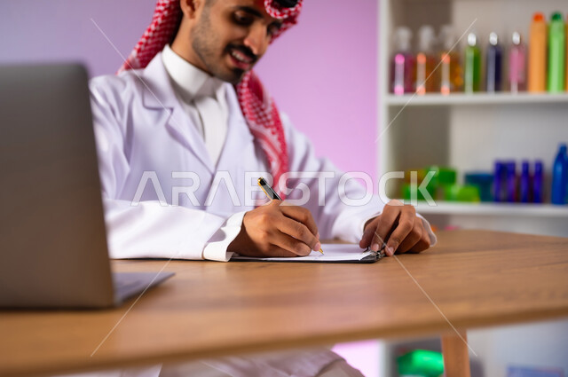استخدام الأجهزة والتقنيات الحديثة والمتطورة, الادوية والمستلزمات الطبية، مفهوم الصيدلة والرعاية الصحية، التشييك على قائمة الأدوية, بورتريه لطبيب صيدلاني عربي خليجي سعودي يرتدي المعطف الطبي الأبيض والشماغ يقوم بكتابة الوصفات العلاجية, خلفية ملونة