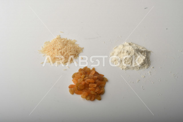 حفنة من الأرز والزبيب والطحين مصورة على خلفية بيضاء .