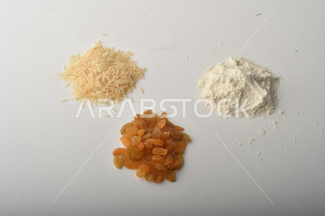 حفنة من الأرز والزبيب والطحين مصورة على خلفية بيضاء .