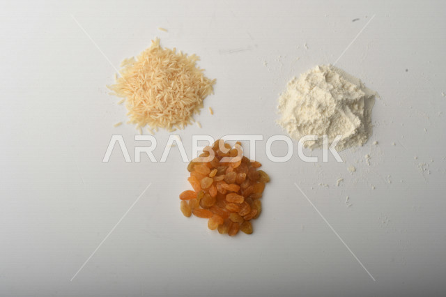 حفنة من الأرز والزبيب والطحين مصورة على خلفية بيضاء .