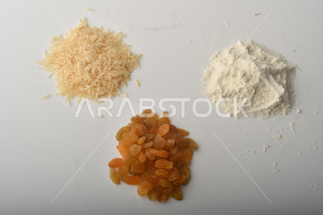 حفنة من الأرز والزبيب والطحين مصورة على خلفية بيضاء . 