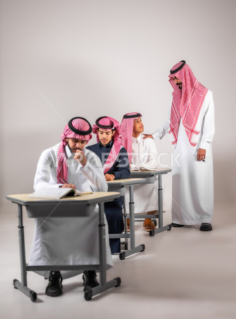 مساعدة المعلم للطلاب بحل اسئلة الدرس, بورتريه لطلاب سعوديون يقومون بأداء الواجبات المدرسية في الصف الدراسي,  التعليم في المملكة العربية السعودية, اهداف التربية و التعليم, خلفية رمادية