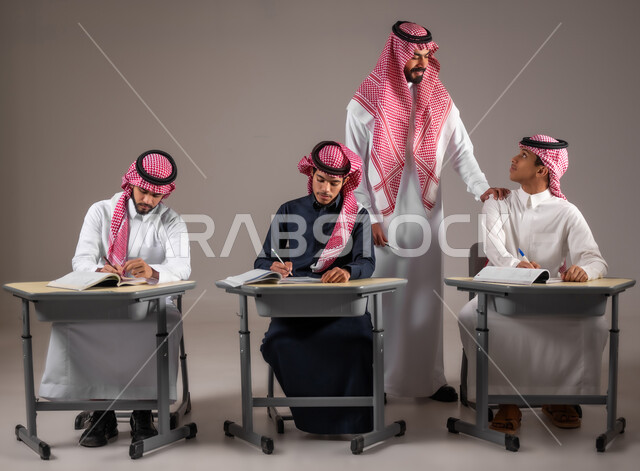 Study and diligence for excellence, education in the Kingdom of Saudi Arabia, a portrait for an Arab Gulf Gulf teacher wearing the traditional garment that monitors students while submitting the end of the semester tests put his hand on the student's shoulder, gray background
