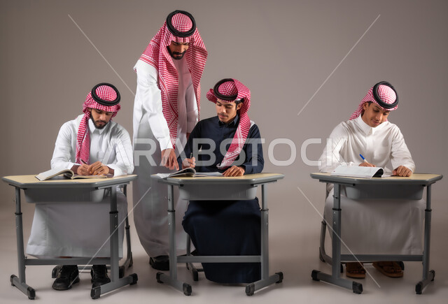 التربية والتعليم في المملكة العربية السعودية، الدراسة والاجتهاد من اجل التفوق، بورتريه لمعلم عربي خليجي سعودي يرتدي الثوب التقليدي يقوم بمراقبة الطلاب اثناء تقديم اختبارات نهاية الفصل الدراسي، يشير باصبع السبابة الى شيء ما، خلفية رمادية