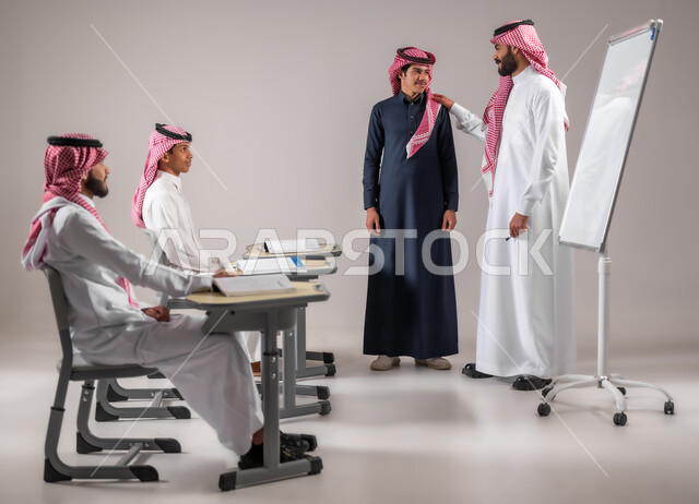 الانجاز والنجاح في المرحلة التعليمية، ايماءات البشاشة والسرور، بورتريه لمعلم عربي خليجي سعودي يرتدي الثوب التقليدي يضع يده على كتف الطالب بتعابير الرضا والمدح، المشاركة الفعالة في الصف، التربية والتعليم بالمناهج المقررة للتلاميذ، مفهوم الاجتهاد و طلب التفوق