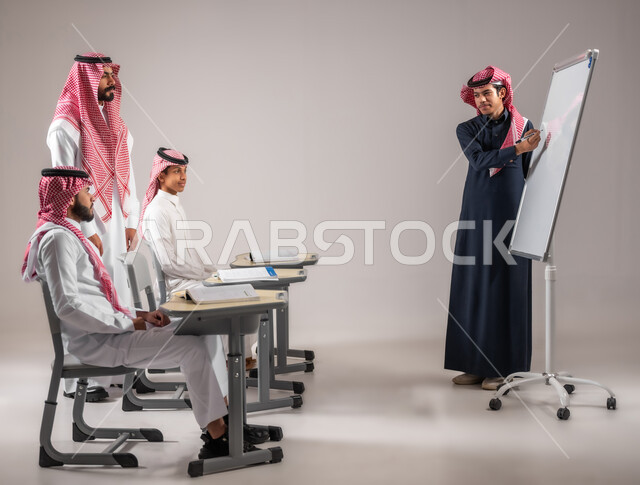 المشاركة الفعالة في الصف، الانجاز و التفوق في المرحلة التعليمية، التربية والتعليم بالمنهاج المقررة، بورتريه لطالب عربي خليجي سعودي يرتدي الثوب التقليدي يقوم بالشرح والإجابة على سؤال المعلم امام التلاميذ، استخدام اللوحة المدرسية البيضاء، خلفية رمادية