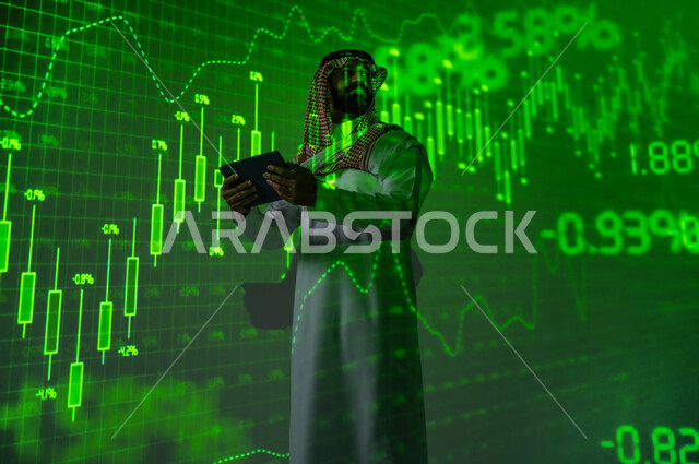 استخدام التقنيات الحديثة و المتطورة , النجاح في التداول المالي , رجل عربي خليجي سعودي يرتدي الثوب التقليدي و الشماغ يقف أمام شاشة مليئة بالأرقام و الإحصائيات يقوم بالاطلاع على الرسم البيانية عبر الجهاز اللوحي , خلفية هولوجرامية ثلاثية الأبعاد