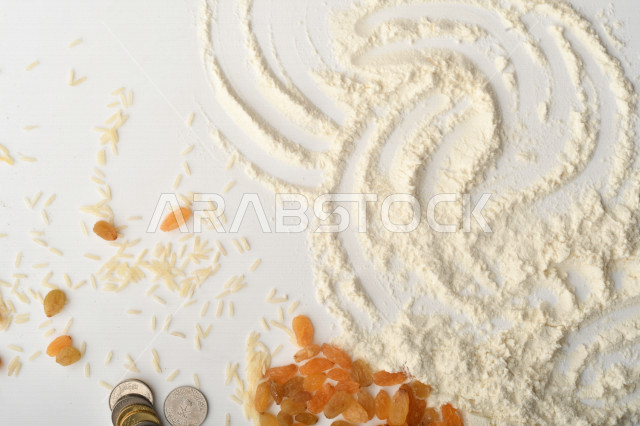 مجموعة من الأرز والزبيب والقمح والطحين والعملات المعدنية على خلفية بيضاء