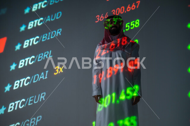 الاستثمار المالي السعودي , التغيرات العالمية بأسعار أسهم البورصة , رجل عربي خليجي سعودي يرتدي الثوب التقليدي و الشماغ يقف أمام شاشة مليئة بالأرقام و الإحصائيات , خلفية هولوجرامية ثلاثية الأبعاد