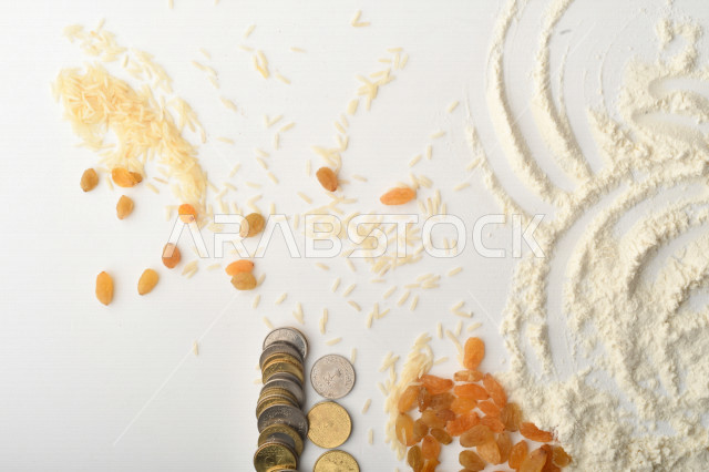 مجموعة من الأرز والزبيب والقمح والطحين والعملات المعدنية على خلفية بيضاء