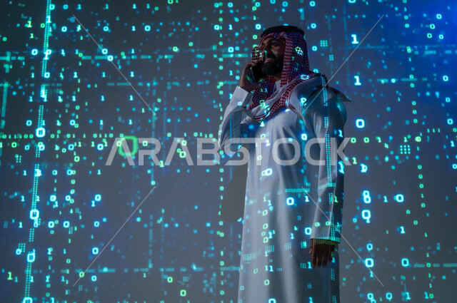 إجراء اتصال هاتفي عبر الجوال , مفهوم التطور التقني , رجل عربي خليجي سعودي يرتدي الثوب التقليدي و الشماغ يمسك هاتفه المحمول بيده , التواصل مع الأهل و الأصدقاء , خلفية هولوجرامية ثلاثية الأبعاد