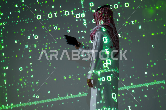 استخدام الأجهزة التقنية الحديثة , مفهوم التطور و النمو الرقمي  , رجل عربي خليجي سعودي يرتدي الثوب التقليدي و الشماغ يمسك الجهاز اللوحي بيده , عرض شاشة سوداء فارغة عبر التابلت , خلفية هولوجرامية ثلاثية الأبعاد