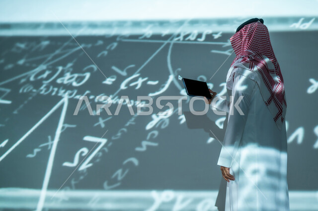استخدام الأجهزة الحديثة , التطور العلمي و التقني , رجل عربي خليجي سعودي يرتدي الثوب التقليدي و الشماغ يمسك الجهاز اللوحي بيده , عرض شاشة سوداء فارغة عبر التابلت, خلفية هولوجرامية ثلاثية الأبعاد