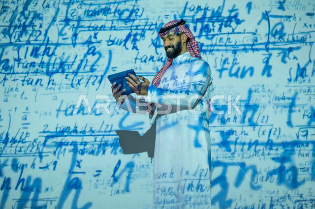 الأرقام والحسابات في مادة الرياضيات، دمج العلم بالتكنولوجيا، رجل عربي خليجي سعودي يرتدي الثوب التقليدي والشماغ يحمل بيده جهار لوحي , التطور العلمي و التقني في المملكة العربية السعودية, عرض شاشة سوداء فارغة, خلفية قوانين خوارزميات رياضية