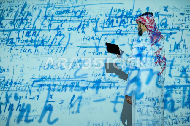 دمج العلم بالتكنولوجيا، أرقام وحسابات في مادة الرياضيات، رجل عربي خليجي سعودي يرتدي الثوب التقليدي والشماغ يحمل بيده جهار لوحي , التطور العلمي و التقني في المملكة العربية السعودية, عرض شاشة سوداء فارغة, خلفية قوانين خوارزميات رياضية