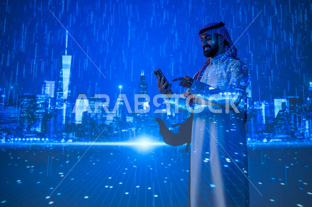 ايماءات السعادة والفرح، استخدام الأجهزة الالكترونية، تقدم وتطور التقنية والتكنولوجيا الحديثة، الاستفادة من التقنيات الحديثة، شاب عربي سعودي خليجي يرتدي الزي التقليدي يمسك بيده الهاتف المحمول يقف تحت المطر أمام الأبراج وناطحات السحاب، الأجواء الممطرة في المدينة