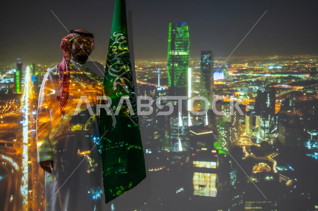الأبراج والمنشأت المعمارية، ذكرى اليوم الوطني للسعودية في 23 سبتمبر، الاحتفال بالأعياد والمناسبات الوطنية، رجل عربي خليجي سعودي مبتسم يرتدي الزي التقليدي يقف بجانب علم المملكة العربية السعودية يحتفل يوم العلم السعودي في11 مارس، مركز الملك عبدالله المالي في الرياض