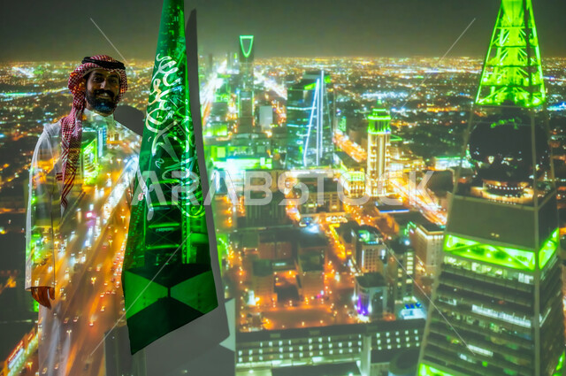 Al Faisaliah Tower in Riyadh, commemorating Saudi National Day on September 23, celebrating national holidays and events, a smiling Saudi Gulf Arab man wearing traditional clothing standing next to the flag of the Kingdom of Saudi Arabia celebrating Saudi Flag Day on March 11, looking at the camera with gestures of happiness and pleasure