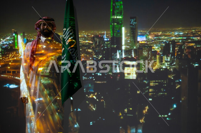ذكرى اليوم الوطني للسعودية في 23 سبتمبر، الاحتفال بالأعياد والمناسبات الوطنية، رجل عربي خليجي سعودي مبتسم يرتدي الزي التقليدي يقف بجانب علم المملكة العربية السعودية يحتفل يوم العلم السعودي في11 مارس، الخلفية برج الفيصلية في الرياض، أبراج وناطحات سحاب مضيئة