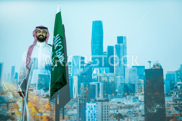 الأعياد والمناسبات الوطنية، الاحتفال بيوم العلم السعودي في11 مارس، ذكرى اليوم الوطني للسعودية في 23 سبتمبر، رجل عربي خليجي سعودي مبتسم يرتدي الزي التقليدي ينظر إلى الكاميرا ويقف بجانب علم المملكة العربية السعودية، الخلفية مركز الملك عبدالله المالي كافد في الرياض