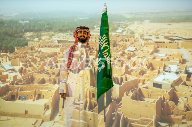 الاحتفال بالأعياد والمناسبات الوطنية، مناطق أثرية محلية، ذكرى اليوم الوطني للسعودية في 23 سبتمبر، رجل عربي خليجي سعودي مبتسم يرتدي الزي التقليدي يقف بجانب علم المملكة العربية السعودية يحتفل يوم العلم السعودي في11 مارس، الخلفية قصر سلوى الدرعية البجيري في الرياض