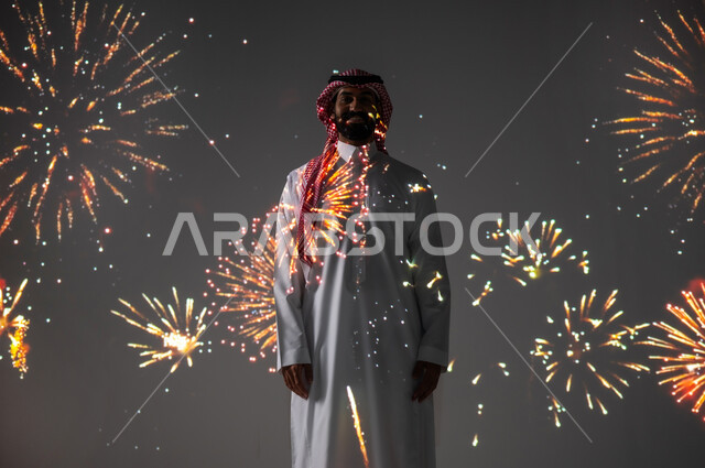 الاستمتاع بالمفرقعات والألعاب النارية في الأعياد والمناسبات، المشاركة بالأنشطة الترفيهية والفعاليات الاحتفالية، شاب عربي خليجي سعودي مبتسم يرتدي الزي التقليدي  ينظر إلى الكاميرا، ايماءات الفرح والسعادة والبهجة