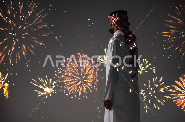 الاستمتاع بالمفرقعات والألعاب النارية في الأعياد والمناسبات، المشاركة بالأنشطة الترفيهية والفعاليات الاحتفالية، شاب عربي خليجي سعودي مبتسم يرتدي الزي التقليدي يشاهد الأضواء والاحتفالات