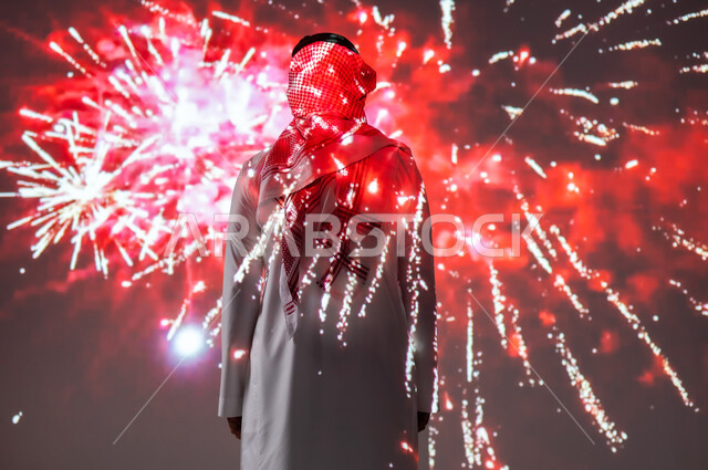 الاستمتاع بالمفرقعات والألعاب النارية في الأعياد والمناسبات، المشاركة بالأنشطة الترفيهية والفعاليات الاحتفالية، شاب عربي خليجي سعودي مبتسم يرتدي الزي التقليدي يشاهد الأضواء والاحتفالات