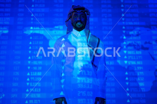 التغيرات العالمية بأسعار أسهم البورصة , صورة من الخلف لرجل عربي خليجي سعودي يرتدي الثوب التقليدي و الشماغ يقف أمام شاشة مليئة بالأرقام و الإحصائيات, خلفية هولوجرامية ثلاثية الأبعاد لخريطة العالم باللون الأزرق