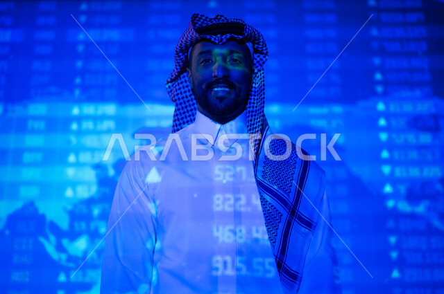 التغيرات العالمية بأسعار أسهم البورصة , صورة من الخلف لرجل عربي خليجي سعودي يرتدي الثوب التقليدي و الشماغ يقف أمام شاشة مليئة بالأرقام و الإحصائيات, خلفية هولوجرامية ثلاثية الأبعاد لخريطة العالم باللون الأزرق