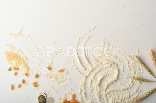 حفنة من الأرز والقمح والزبيب والطحين مصورة على خلفية بيضاء .