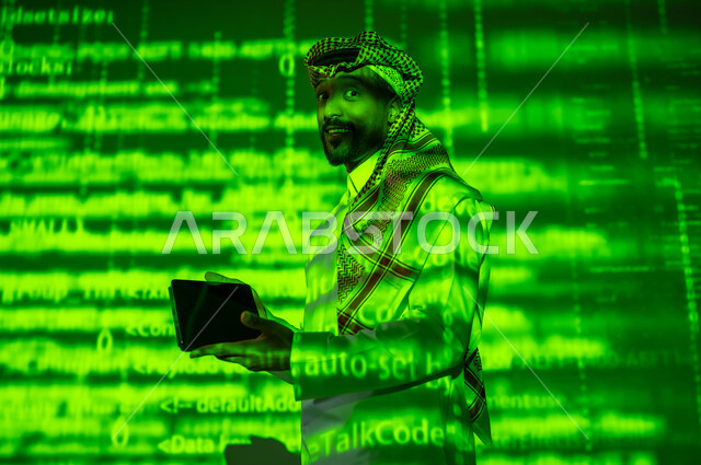 رموز واحرف وارقام، استخدام التقنيات الحديثة, دمج العلم بالتكنولوجيا، أرقام وحسابات في مادة الرياضيات، رجل عربي خليجي سعودي يرتدي الثوب التقليدي والشماغ يحمل بيده جهاز التابلت اللوحي, التطور العلمي و التقني في المملكة, خلفية خضراء للقوانين والمعادلات