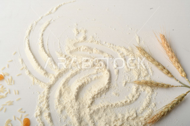 حفنة من الأرز والقمح والزبيب والطحين مصورة على خلفية بيضاء .