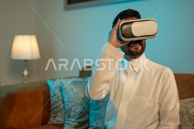 المتعة و التسلية والتفاعل بمتابعة المسلسلات ، مشاهدة أفلام ثلاثية الابعاد عبر نظارة الواقع الإفتراضي الحديث ، شاب عربي خليجي سعودي يرتدي نظارات العالم الخيالي , التطور والتقدم التقني والتكنولوجي , إيماءات وجه ويدين تدل على الحماس