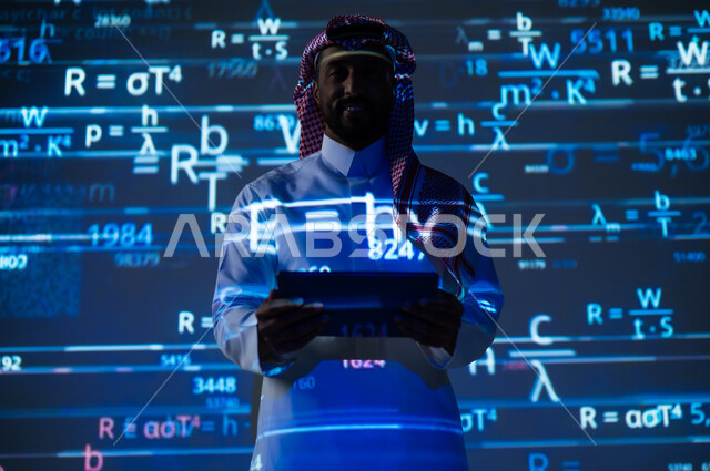 استخدام التقنيات الحديثة, دمج العلم بالتكنولوجيا، أرقام وحسابات في مادة الرياضيات، رجل عربي خليجي سعودي يرتدي الثوب التقليدي والشماغ يحمل بيده جهاز التابلت اللوحي, التطور العلمي و التقني في المملكة العربية السعودية, خلفية زرقاء للقوانين والمعادلات