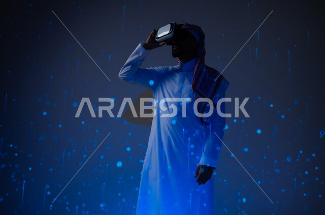 التطور التكنولوجي والرقمي في المملكة العربية السعودية، شاب عربي سعودي خليجي يرتدي الثوب التقليدي يضع نظارات الفي ار وينظر بايماءات السعادة والفخر، رؤية مستقبلية سعودية ٢٠٣٠، خلفية هيولوجرامية ثلاثية الأبعاد لخطوط ونقاط مضيئة