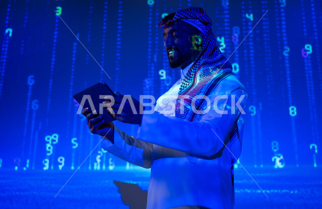 ايماءات السرور والفخر، التطور الرقمي والتكنولوجي في المملكة العربية السعودية، استخدام الأكواد والخوارزميات المتطورة، لغات برمجية عالمية، شاب عربي سعودي خليجي يرتدي الثوب التقليدي يمسك بيده جهاز لوحي، خلفية هيولوجرامية ثلاثية الأبعاد للأرقام المضيئة