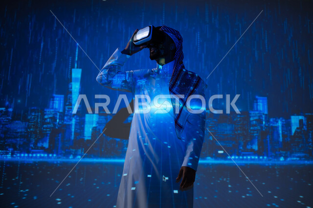 الأجواء الممطرة في المملكة العربية السعودية، رؤية سعودية مستقبلية٢٠٣٠، مشاهدة فصل الشتاء الماطر، شاب عربي سعودي خليجي يرتدي الزي التقليدي والشماغ يقف تحت المطر أمام الأبراج وناطحات السحاب ويضع تظارات الفي ار، زيارة الأماكن المحلية