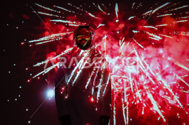 الاستمتاع بالألعاب النارية والمفرقعات في الأعياد والمناسبات، المشاركة بالأنشطة الترفيهية والفعاليات الاحتفالية، شاب عربي خليجي سعودي يرتدي الزي التقليدي والشماغ يقف أمام الأضواء والاحتفالات وينظر إلى الكاميرا