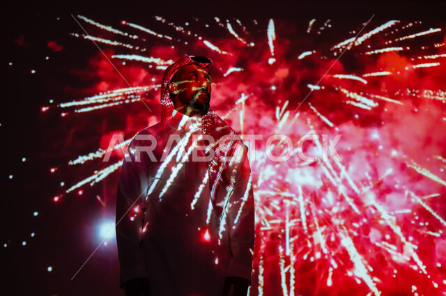 رؤية سعودية مستقبلية٢٠٣٠، ايماءات السعادة والفرح، المشاركة بالأنشطة الترفيهية والفعاليات الاحتفالية، الاستمتاع بالألعاب النارية والمفرقعات في الأعياد والمناسبات، شاب عربي خليجي سعودي يرتدي الزي التقليدي والشماغ يقف أمام الأضواء والاحتفالات وينظر إلى الأعلى