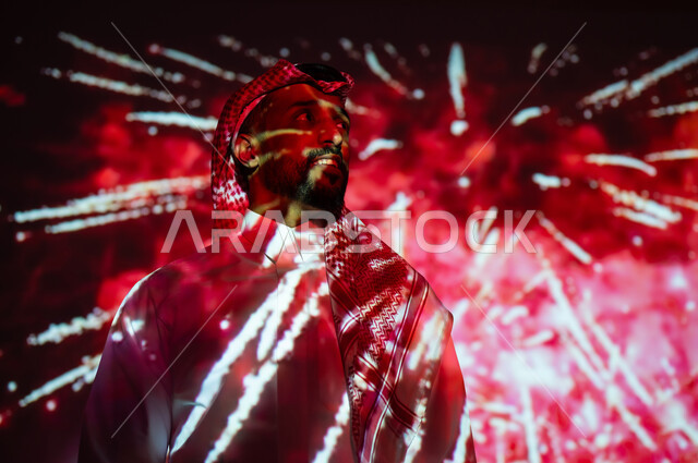 الاستمتاع بالمفرقعات والألعاب النارية في الأعياد والمناسبات، المشاركة بالأنشطة الترفيهية والفعاليات الاحتفالية، شاب عربي خليجي سعودي مبتسم يرتدي الزي التقليدي والشماغ يشاهد الأضواء والاحتفالات