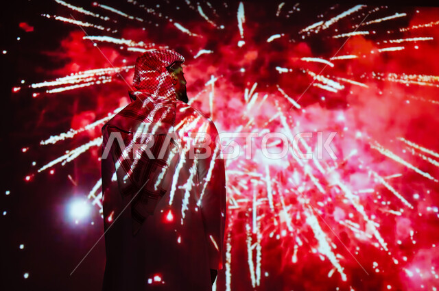 الاستمتاع بالمفرقعات والألعاب النارية في الأعياد والمناسبات، المشاركة بالأنشطة الترفيهية والفعاليات الاحتفالية، شاب عربي خليجي سعودي يرتدي الزي التقليدي والشماغ يشاهد الأضواء والاحتفالات