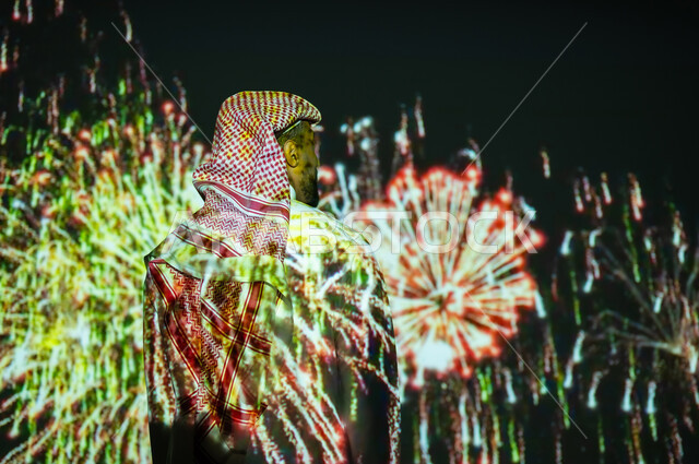 الاستمتاع بالمفرقعات والألعاب النارية في الأعياد والمناسبات، المشاركة بالأنشطة الترفيهية والفعاليات الاحتفالية، شاب عربي خليجي سعودي مبتسم يرتدي الزي التقليدي والشماغ يشاهد الأضواء والاحتفالات