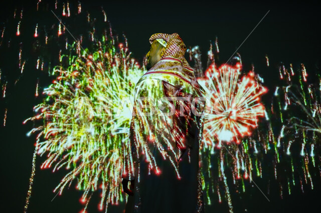 المشاركة بالأنشطة الترفيهية والفعاليات الاحتفالية، الاستمتاع بالألعاب النارية والمفرقعات في الأعياد والمناسبات، شاب عربي خليجي سعودي يرتدي الزي التقليدي والشماغ ينظر إلى الأضواء والاحتفالات