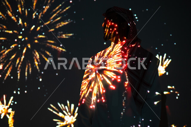 الأنشطة الترفيهية والفعاليات الاحتفالية، رجل عربي خليجي سعودي يرتدي الثوب التقليدي ينظر إلى المفرقعات في وقت الليل، الاستمتاع بالألعاب النارية في الأعياد والمناسبات الوطنية، الاحتفالات والمهرجانات في المملكة العربية السعودية، الاحتفال باليوم الوطني السعودي