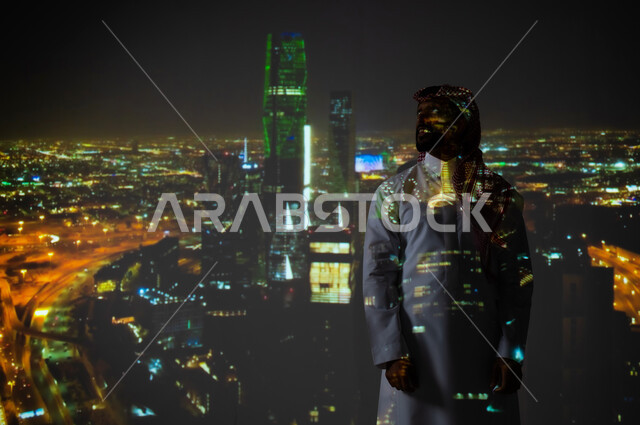 الاحتفال باليوم الوطني 23 سبتمبر في المملكة العربية السعودية، يوم العلم السعودي 11 مارس، رجل عربي خليجي سعودي يرتدي الثوب التقليدي يقف أمام مركز الملك عبدالله المالي في الرياض, الأبراج وناطحات السحاب المضيئة باللون الأخضر، رؤية مستقبلية سعودية 2030
