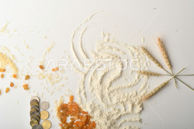 مجموعة من الأرز والزبيب والقمح والطحين والعملات المعدنية على خلفية بيضاء
